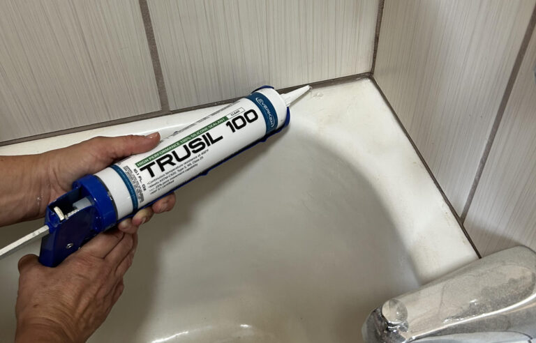 Trusil 100 caulk tube in caulk application gun being used in bathroom around edges of tub
